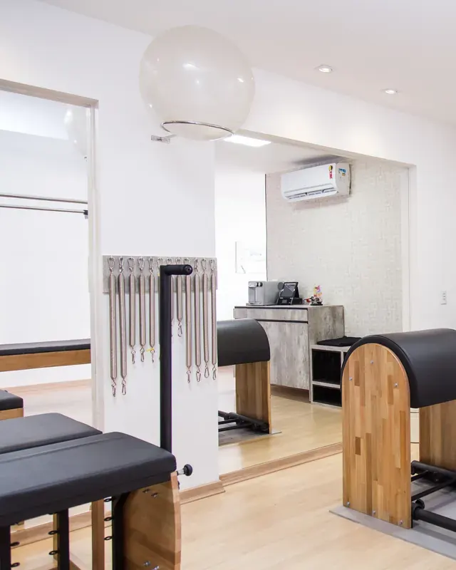 Sala do studio com maca de atendimento, barril e cadeira de pilates
