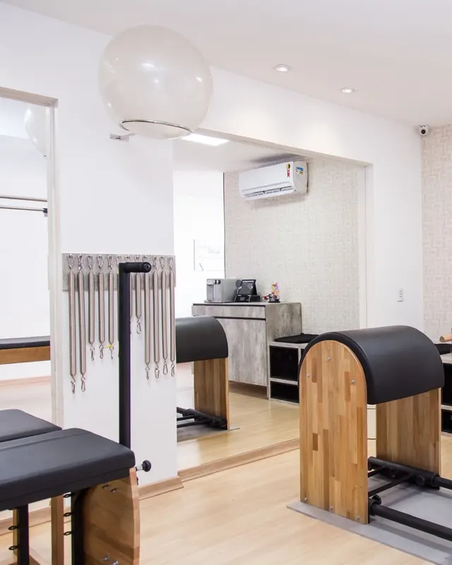Barril e cadeira de pilates perto da janela, com o espaldar ao fundo